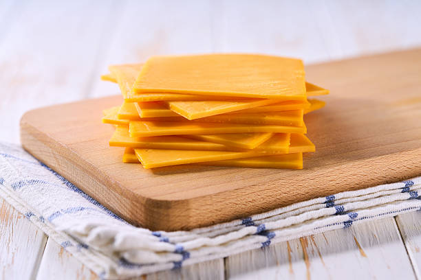 istock cheddar cheese slices on a wooden table, close up. 2211471273