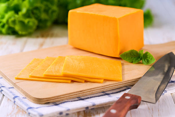 istock sliced natural cheese cheddar on on a white wooden table, selective focus. 2211471320