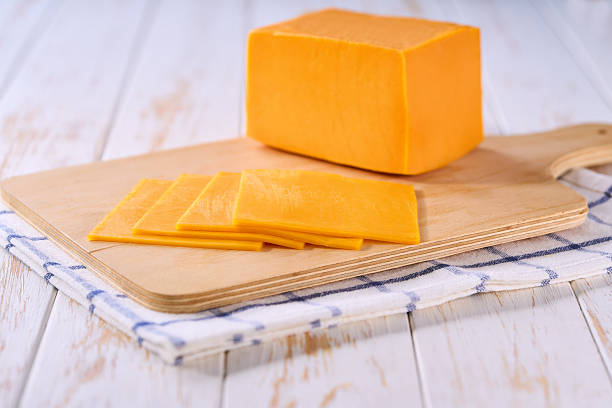 istock Slices of cheddar cheese on a cutting board, selective focus. 2211471339