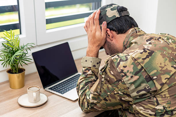 istock Stressed soldier teleworking from home office holding his head 2211475049