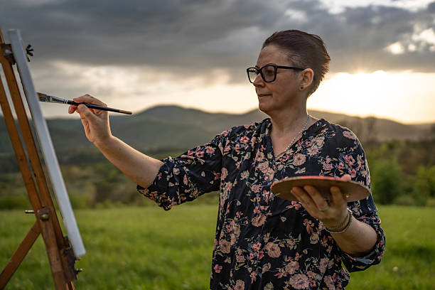Woman Painting on an Easel Outdoors During a Beautiful Sunset