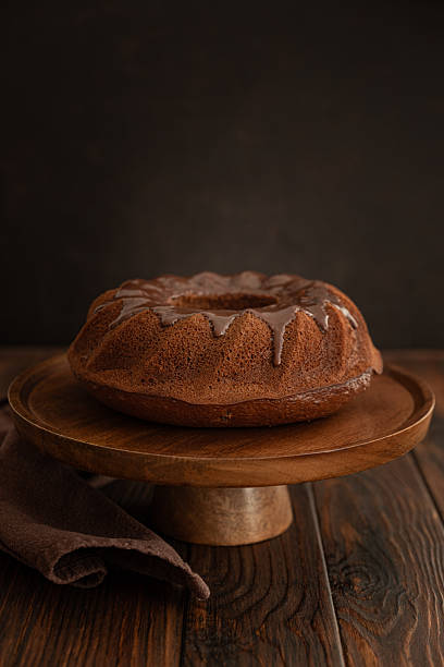 istock Chocolate cake with chocolate icing on dark wooden table. Low key. Front view 2211477427