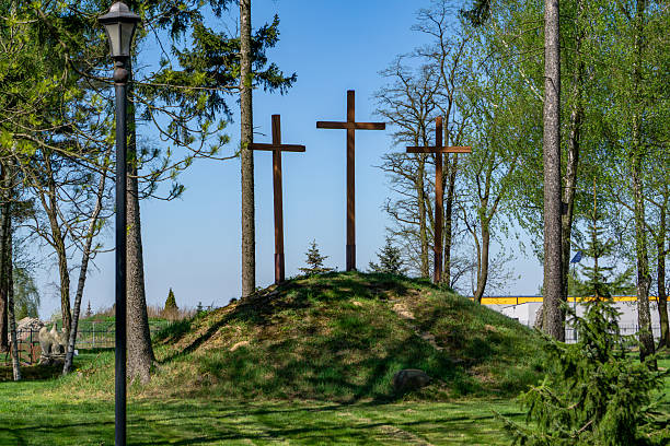 Three crosses placed on a small hill in the cemetery, symbolizing Golgotha. A place of reflection and remembrance, surrounded by trees and greenery.