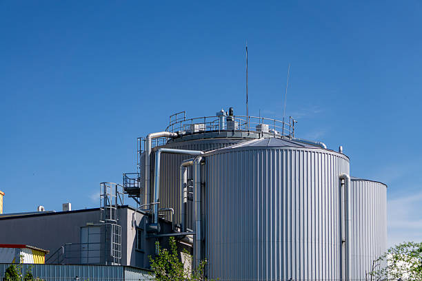 istock an industrial complex dominated by a large, cylindrical metal tank is visible. The structure is surrounded by technical infrastructure, such as pipes, railings and stairs. The facility is located under a cloudless, blue sky 2211478057