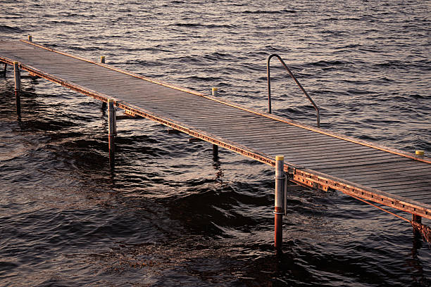 A wooden pier stretches over tranquil waters during sunset, with soft waves creating a serene atmosphere and inviting the viewer to contemplate the beauty of nature.