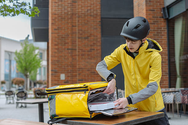 istock Delivery person arranging pizza boxes in a bag outside a restaurant 2211483046