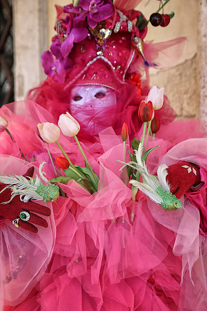 People in traditional Venetian carnival costumes pose for a photo in a historic courtyard during the Venice Carnival. Venice, Italy – 02.16. 2025