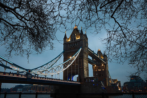 Tower Bridge in London, UK, at the beginning of night, brightly illuminated with reflections on the River Thames.
