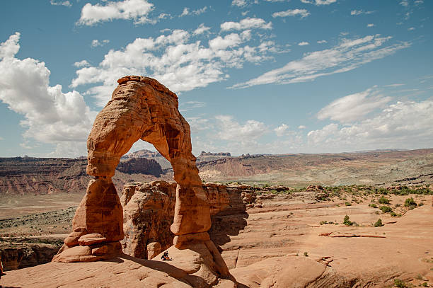 istock Under the Arch: Two Friends Rest Beneath Delicate Arch on a Sunny Day 2211490088