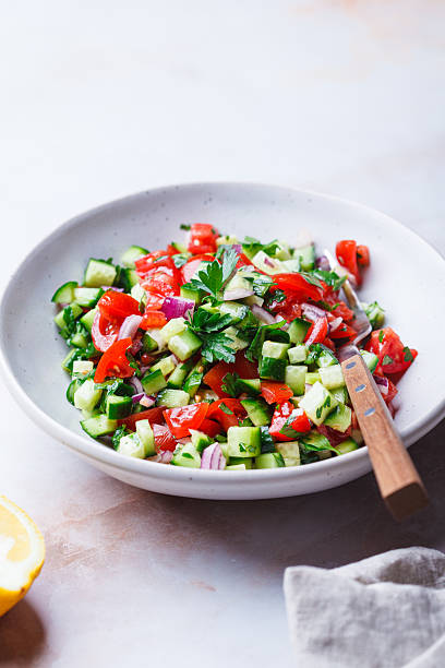 istock Vegetable salad with tomatoes, cucumbers, onions and parsley. 2211490400