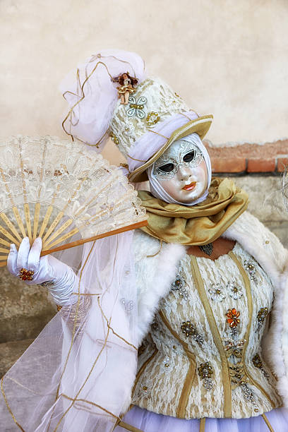03/02/2025 Venice - Italy\n\nSan Marco Square - where most of the dressed out participants gather to show off - wander around and get photographed. This woman have a pale purple tulle costume on with organza. Holding a beautiful fan.