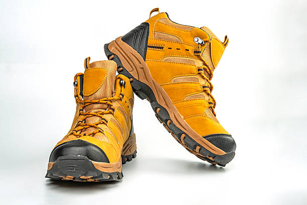 istock Image of high-quality hiking boots with sturdy construction and robust lacing systems, featuring a mix of mustard or yellowish tones on the upper, likely for outdoor sports gear advertising 2211490745