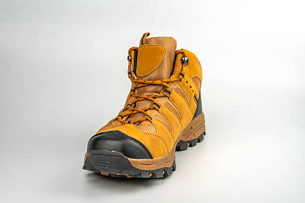 istock A sturdy, adjustable hiking boot in yellow and brown colors with a grippy tread pattern is shown against a neutral background The image showcases the boots design for outdoor activities like hiking 2211490823
