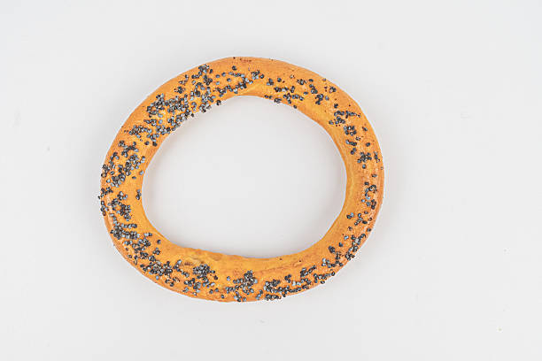 istock Image shows a freshly baked circular orange bagel with sesame seeds on a light background 2211490977