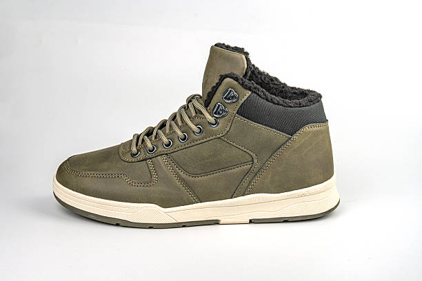 istock A high-top sneaker with a dark olive green upper, contrasting tan stitching and trim, white rubber sole, and unique lace closure, displayed against a white background 2211491457