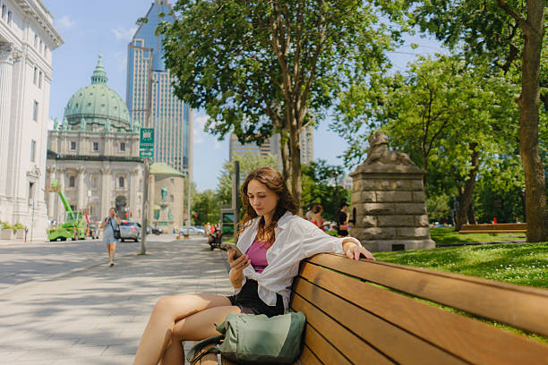 Woman using smartphone sitting on the bench in Montreal, Quebec, Canada
