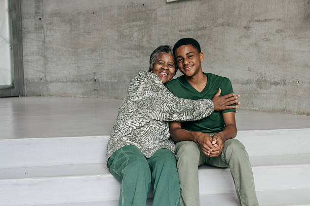 A grandmother and her teenage grandson share a heartfelt moment, enjoying each other’s company with bright smiles.