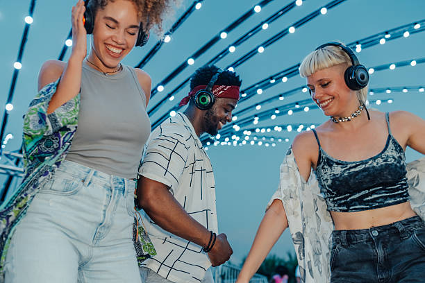 istock Young people dancing together at silent disco with headphones 2211508362