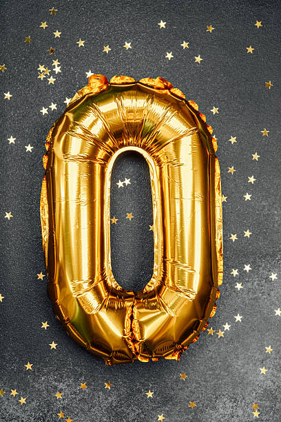 istock Golden number zero balloon on black surface with scattered gold stars 2211508742