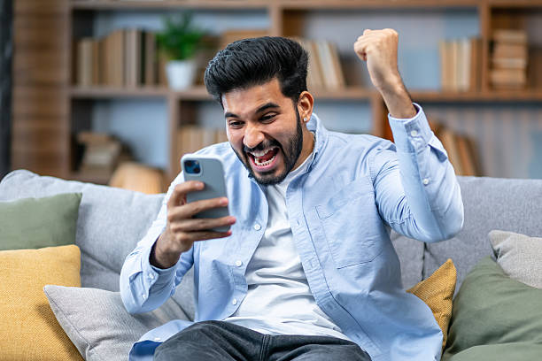istock Excited overjoyed indian man winner holding smartphone feeling euphoric with mobile online bet bid game win, happy ecstatic african guy looking at cell phone celebrate receiving reading good news 2211510234
