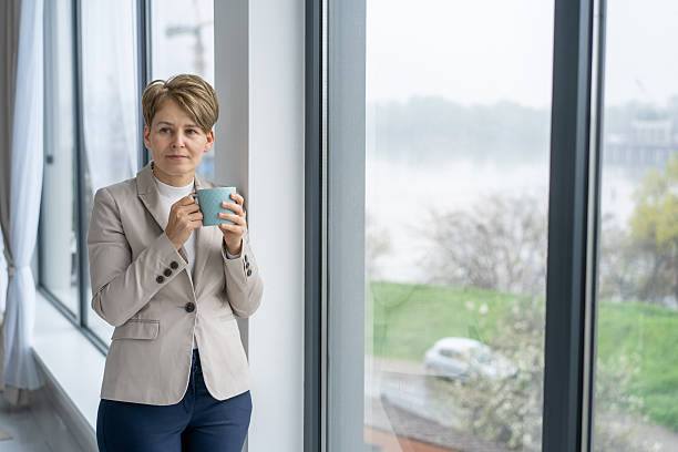istock Woman holding a cup, looking out the window thoughtfully 2211517356