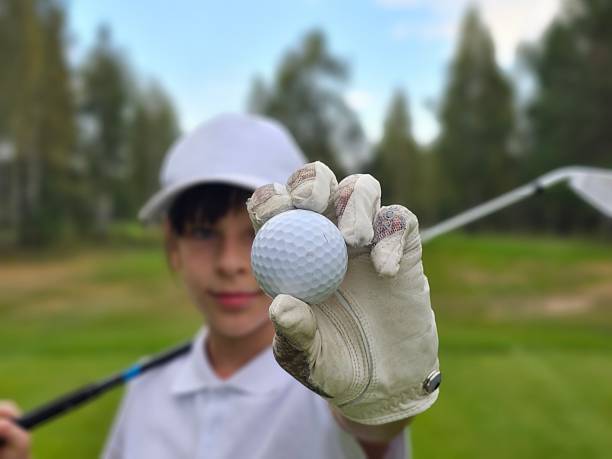 Golfer proudly displays ball with swing ready on lush green course during sunny day