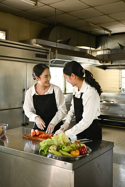 istock Two women are cutting vegetables on a counter in a kitchen. 2211536896