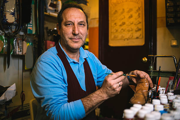 istock Shoemaker painting a shoe in his workshop 2211539240
