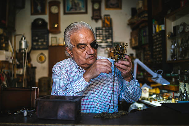 istock Senior watchmaker repairing clock mechanism in workshop 2211539265