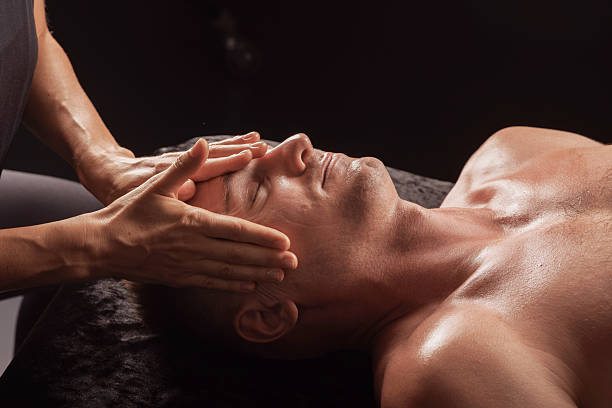istock Facial massage session for man in spa, hands applying pressure to forehead and temples. 2211541716
