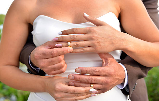 istock Bride and Groom Embrace While Exchanging Wedding Rings 2211542282