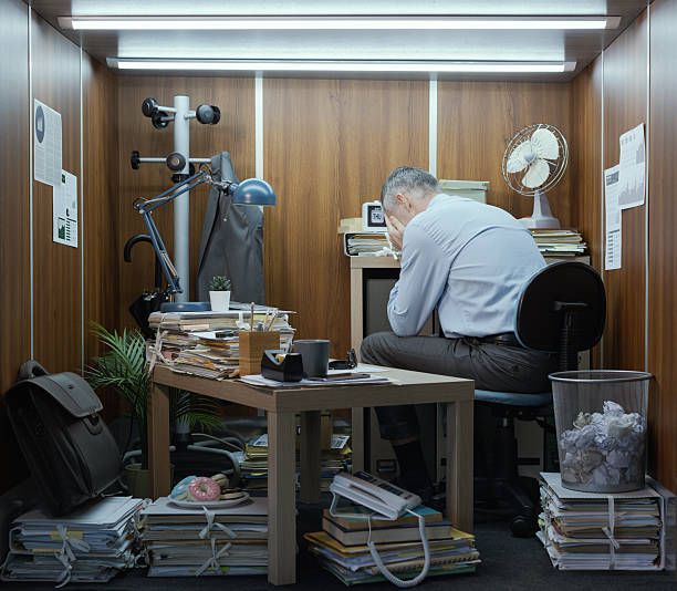 Frustrated hopeless businessman working in a small cheap messy office, lack of space concept