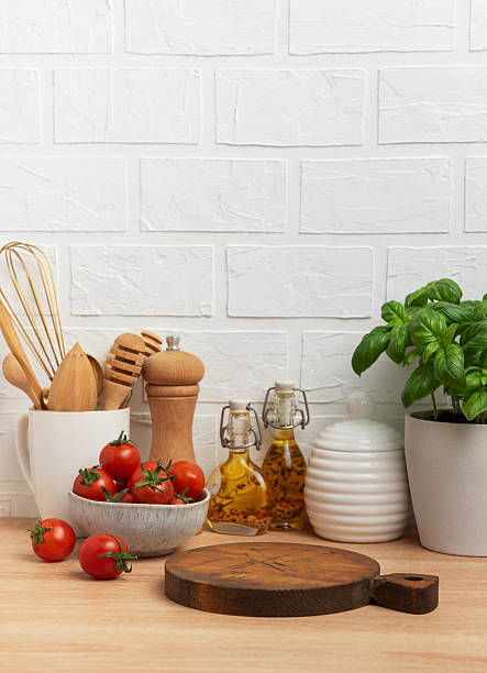 istock Kitchen countertop with cutting board, tomatoes, spices, and basil plant 2211543228