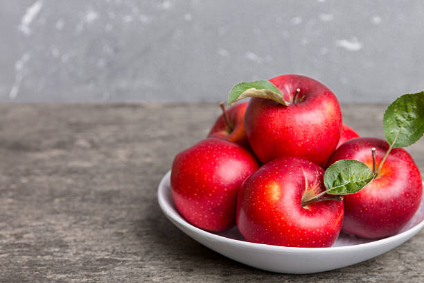 istock juicy red apples in a bowl or plate on the table top view. Copy space 2211543615