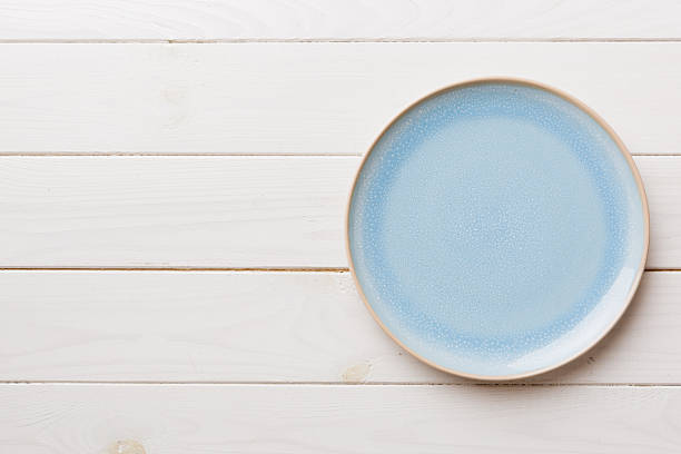 Top view of empty blue plate on wooden background. Empty space for your design.