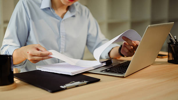 istock Focused businessman working with laptop and reviewing documents at workspace 2211543759