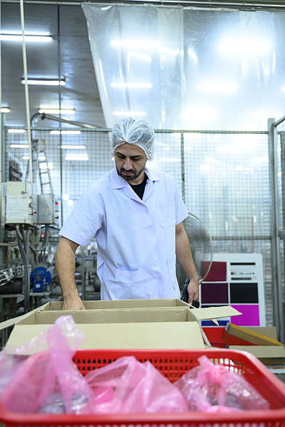 istock Food factory worker checking packaged products in food processing facility 2211543807