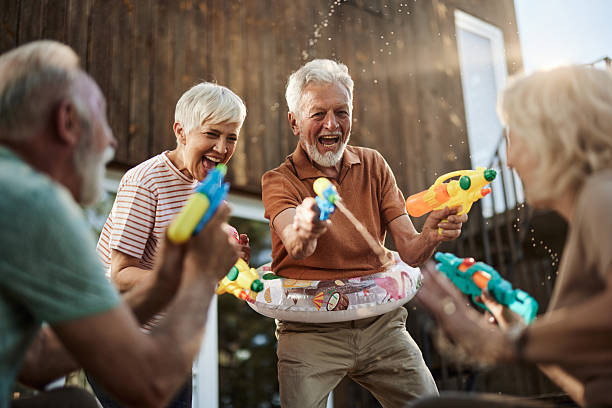 istock Happy senior couples having fun during water gun fight on a terrace. 2211547176