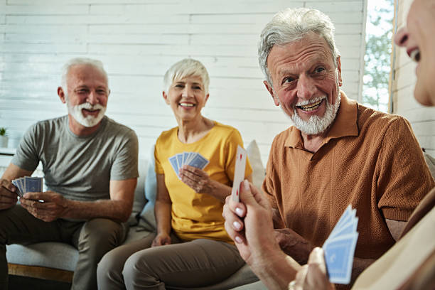 istock Happy senior couples talking while playing cards at home. 2211549314