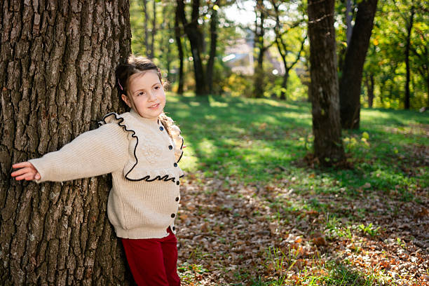 Cute girl enjoying nature while leaning against a tree in park. Copy space