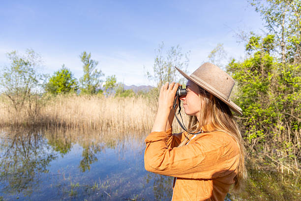 Woman Birdwatching in a Wetland with Binoculars