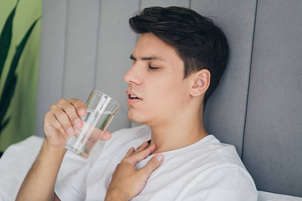 istock Young man resting in bed drinking water in the morning light. 2211551678