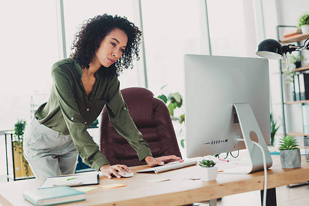 istock Confident businesswoman working at a computer in a modern office, emphasizing professionalism and productivity in a bright work environment 2211552888