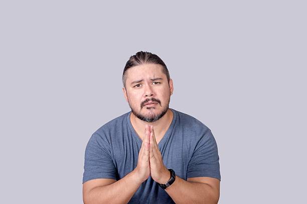 istock A man desperately asks for forgiveness or pleading for help. Clasping his hands together to express the urgency. 2211553042
