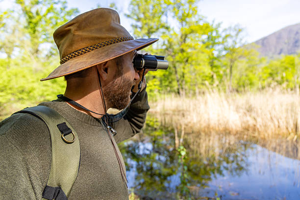 istock Man Birdwatching Near a Tranquil Lake in Nature 2211553048