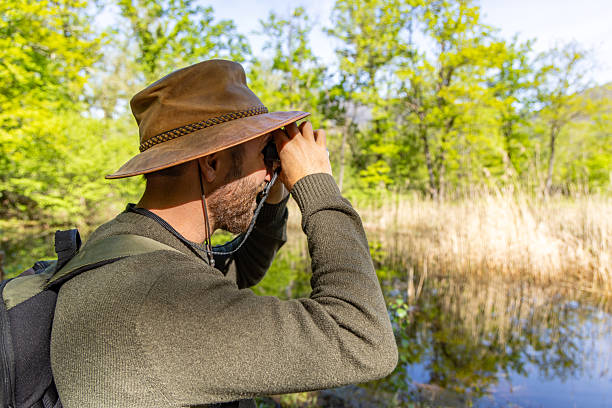 istock Man Birdwatching Near a Tranquil Lake in Nature 2211553058