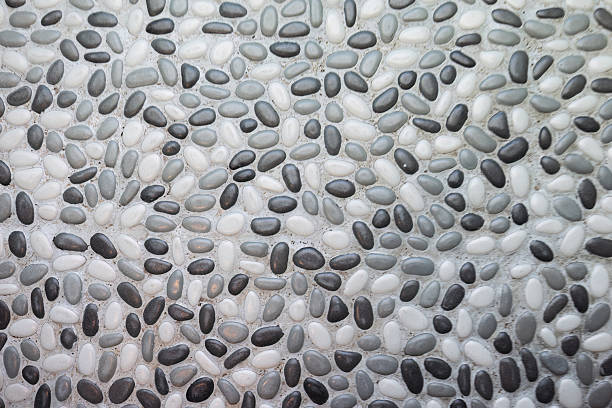 A close-up of a decorative pebble wall showcases a mosaic of smooth black, grey, and white stones arranged in an organic pattern in Zambia near Victoria Falls. This tactile surface adds natural elegance and texture to eco-lodge architecture. This was taken on a tour of the Simalaha Conservancy, a community-based conservation project run by Peace Parks.