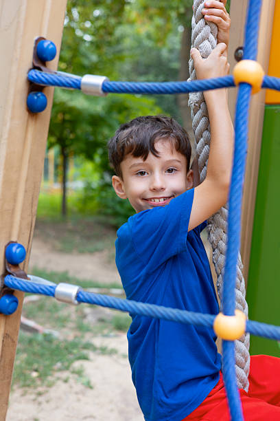 istock Child climbing rope at playground having fun during summer holidays 2211557009