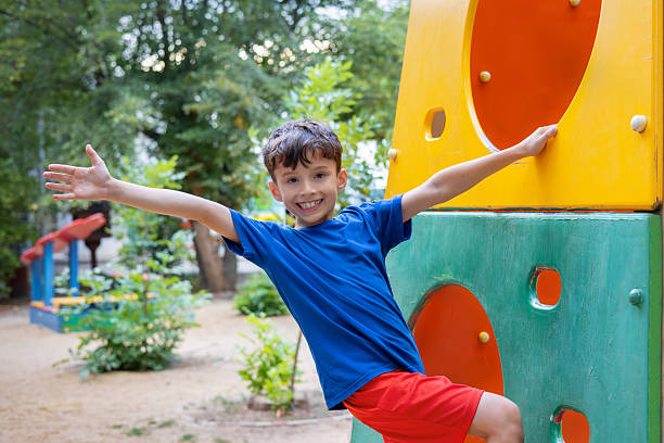 Smiling boy enjoying fun moments while climbing a vibrant playground structure, engaging in outdoor activities and playtime at a lively park filled with joy and laughter