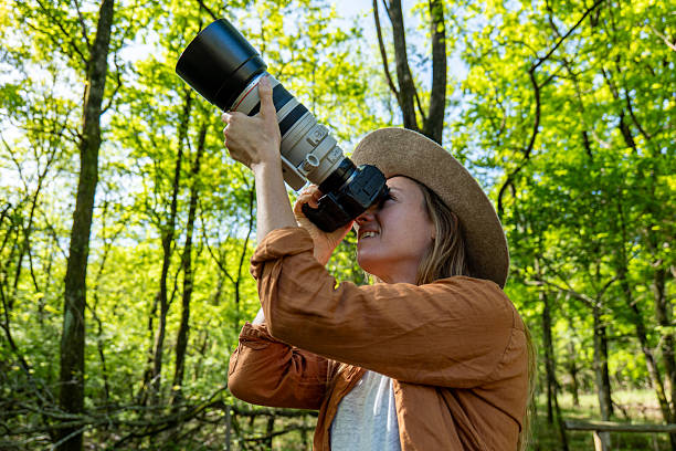 istock Woman Observing Nature with Large Camera Lens in Forest 2211557381